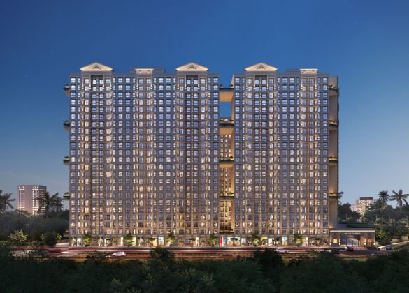Exterior view of the illuminated L3 Living residential towers in Dombivli at twilight. The modern high-rise buildings feature numerous lit windows, showcasing the scale of the development against a darkening sky.